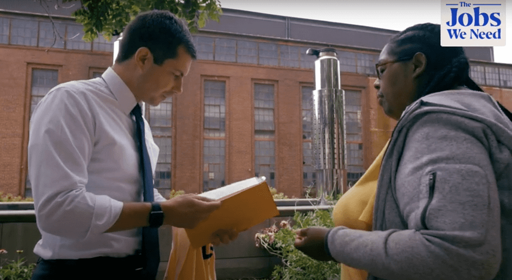Image of PPT Board Member Lisa Gonzalez speaking to Secretary Buttigieg about the Fair Fares report published by PPT last Fall. Ms Lisa is wearing a yellow shirt. Secretary Buttigieg is holding the report, wearing a white shirt and blue tie. They are standing outside the USDOT office in Washington DC.