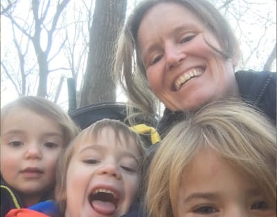 Image description: Barb Warwick, a white woman with long brown hair dressed in a winter coat, is outdoors with her three kids. Everyone is hugging in close together and smiling.