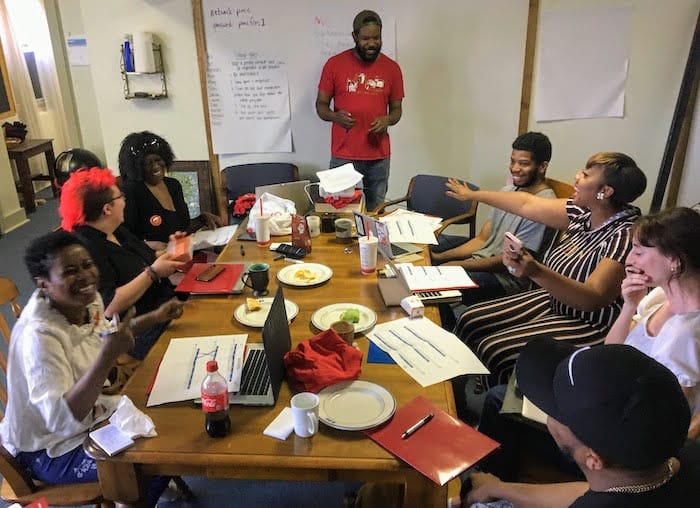 Image of the Beyond the East Busway organizing fellows laughing around a table as they plan the campaign’s next steps.