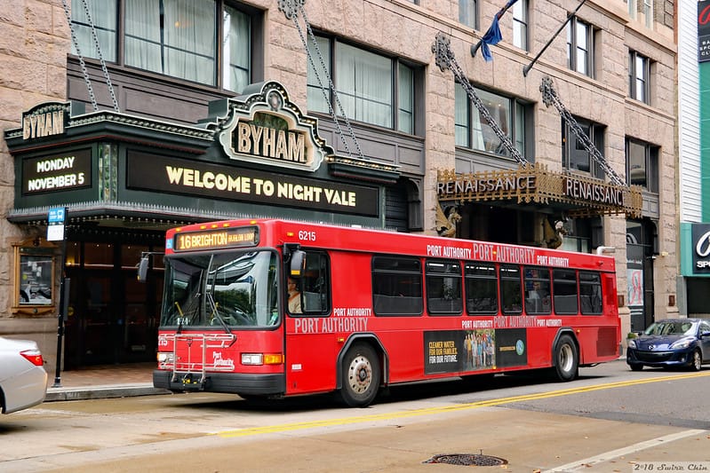 Image Description: Red Port Authority traveling in front of Bynum Theater in downtown PGH. Image from Flickr user: Can Pac Swire